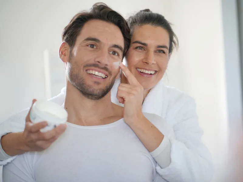 a man and woman moisturizing face skin