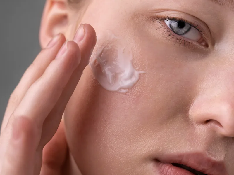 a woman applying facial moisturizer
