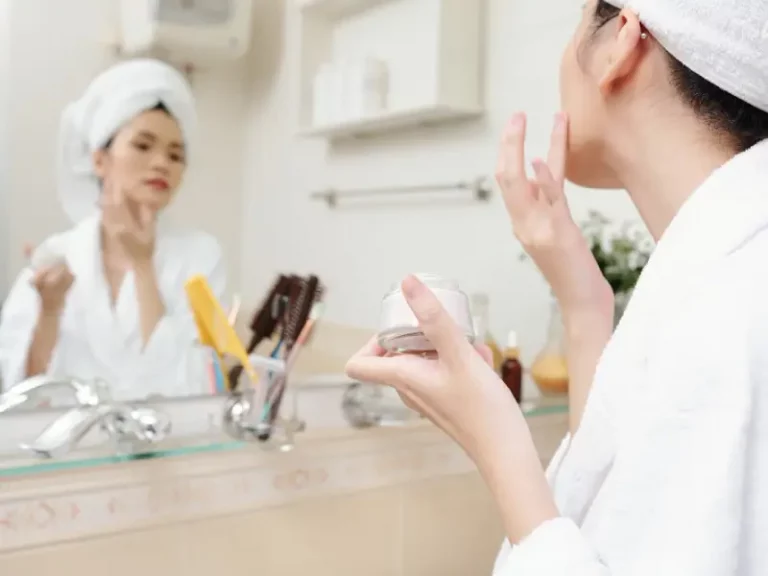 woman in the mirror holding in her hand a korean skincare moisturizer cream